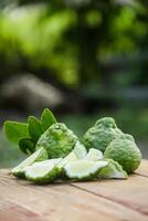 Bergamot fruits or sliced kaffir lime on wooden table and natural green background photo