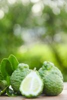 Bergamot fruits or sliced kaffir lime on wooden table and natural green background photo