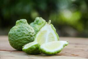 Bergamot fruits or sliced kaffir lime on wooden table and natural green background photo