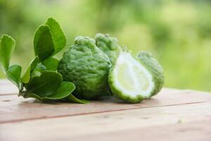 Bergamot fruits or sliced kaffir lime on wooden table and natural green background photo