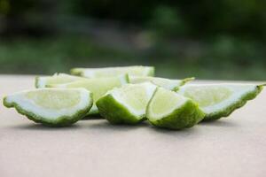 Bergamot fruits or sliced kaffir lime on wooden table and natural green background photo