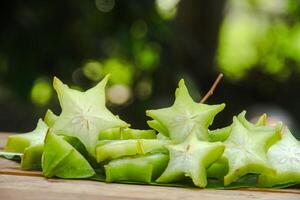Carambola fruit with slice of star fruit on wooden table and natural background photo