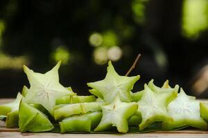 Carambola fruit with slice of star fruit on wooden table and natural background photo