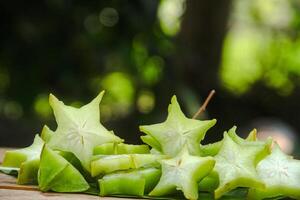 Carambola fruit with slice of star fruit on wooden table and natural background photo