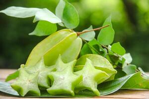 Carambola fruit with slice of star fruit on wooden table and natural background photo