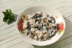 Gatot food with grated coconut topping, Gatot is a typical Indonesian food made from cassava which is dried for some time to produce a distinctive black color photo
