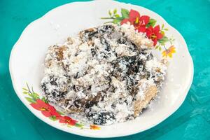 Gatot food with grated coconut topping, Gatot is a typical Indonesian food made from cassava which is dried for some time to produce a distinctive black color photo