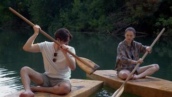 Young man teaches a girl how to hold an oar and row to swim on a surfboard video