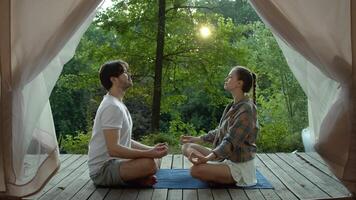 couple est assis vers le bas orienté vers chaque autre dans une paisible réglage et commence à méditer, surplombant le Stupéfiant vue de leur site de camp. video