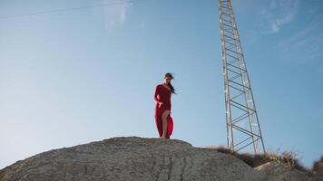 Woman In Red Dresses Dancing On A Hill Near An Electrical Pylon video
