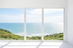 Window with a view of the ocean and green trees photo