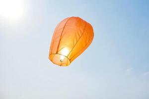 Single Orange Sky Lantern Floating in Blue Sky photo