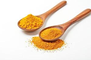 Two wooden spoons filled with yellow spices on a white background photo