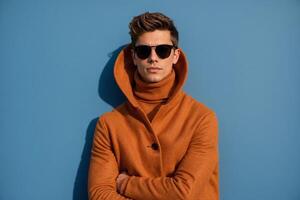 Stylish man in a brown coat and sunglasses against a blue background photo