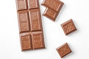 Milk Chocolate Bar Broken into Pieces Isolated on White Background photo