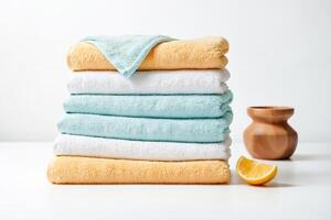 Stack of Soft Towels and a Wooden Vase with a Slice of Lemon on a White Background photo