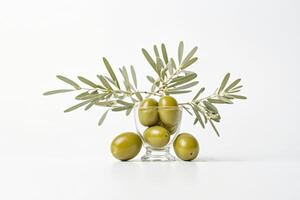 Green Olives with Olive Branch in Glass Bowl on White Background photo