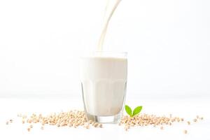 Soy milk pouring into a glass with soy beans photo