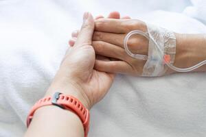 Someone hand holding patient hand during receiving intravenous fluid directly into a vein. photo