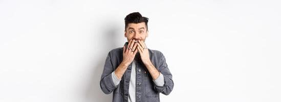 Excited happy man laughing from happiness, look with surprise and disbelief, receive gift, standing on white background photo