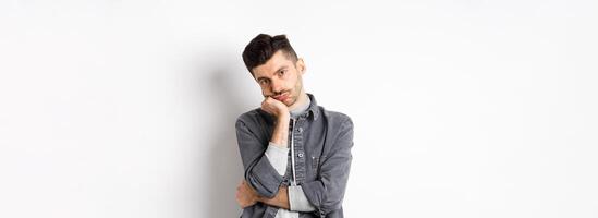 Bored and reluctant stylish guy look at camera without emotions, attend boring meeting, standing on white background photo