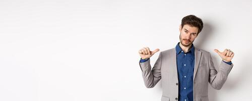 Confident man in business suit looking like professional, pointing at himself, self-promoting, standing on white background photo