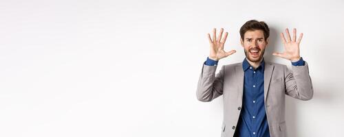 Frustrated man giving up, raising hands up in surrender and screaming, having argument, wearing suit and looking distressed, white background photo