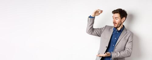 Businessman in suit showing large size and looking excited, making big money, standing on white background photo