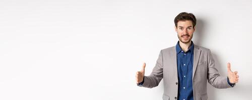 Excited handsome businessman showing long size thing, big object with stretch out hands, standing in suit on white background photo
