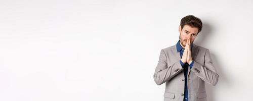 Please help. Pleading man in suit asking for favour, begging you, standing on white background photo