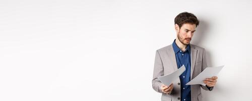 Businessman in suit looking through papers, reading documents at work, standing busy on white background photo