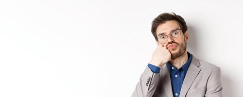 Bored funny office worker in glasses, pouting and holding breath, staring with popped eyes at camera, white background photo