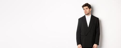 Image of tired man in suit looking left with distressed, gloomy expression, stare left at copy space, standing exhausted over white background photo