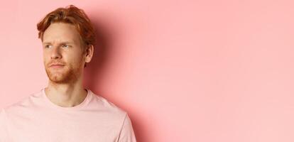 Close up of skeptical and unamused european man, smirk with judgemental face, looking left at banner, standing over pink background photo