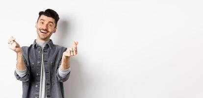 Handsome smiling man showing hand hearts and looking with love at camera, standing on white background photo