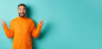 Shopping and advertisement concept. Excited man buyer pointing fingers sideways, showing two choices products, left and right banners, standing over light blue background photo