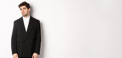 Image of tired man in suit looking left with distressed, gloomy expression, stare left at copy space, standing exhausted over white background photo