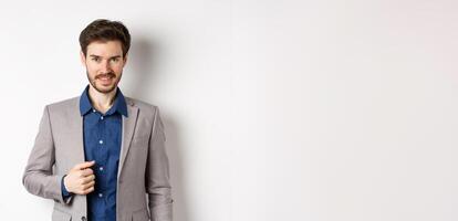 Confident businessman in suit smiling at camera, standing self-assured against white background photo