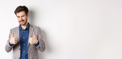 Very good. Smiling handsome male ceo manager showing thumbs up in approval, look proud and satisfied, say yes, approve nice work, standing on white background photo