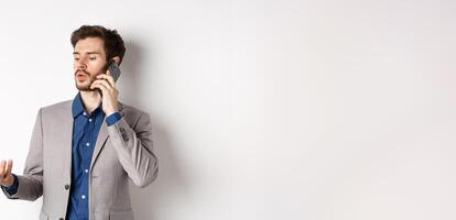 Handsome businessman having business call on phone, gesturing while talking on mobile, having conversation, white background photo