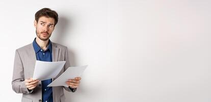 Businessman in suit looking through papers, reading documents at work and thinking, looking aside at logo, standing busy on white background photo