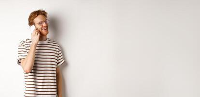 Profile of happy young handsome man talking on mobile phone, looking left and smiling, standing over white background photo
