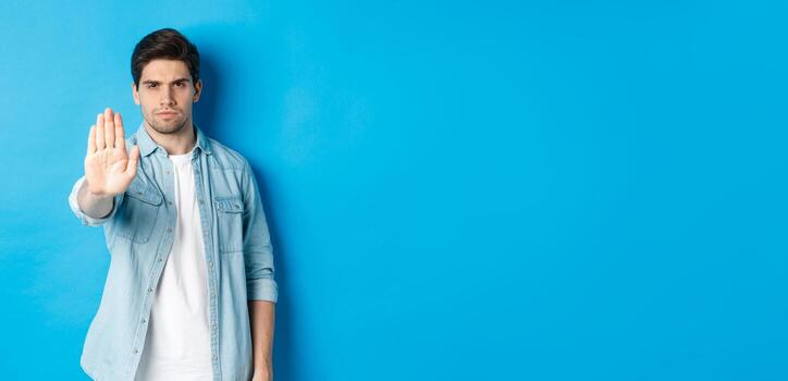 grave hombre ceñudo y diciendo No, extensión mano a tienda detener firmar, prohibir acción, en pie en contra azul antecedentes foto