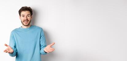 Handsome young man feeling happy for you, pointing hands at camera and praising good work, congratulations gesture, standing over white background photo