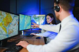 Center of dispatching maintenance. Portrait of cheerful woman and man working via headset microphone while sitting on navigation controller board photo