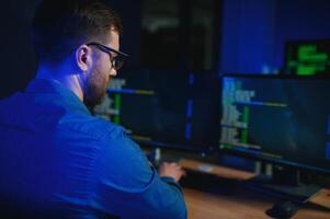 Male programmer working on desktop computer at white desk in office photo