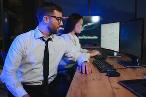 Team of traders working at monitor computer and browsing online in trading office photo