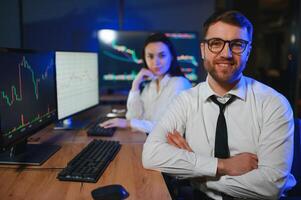 Team of stockbrokers are having a conversation in a dark office with display screens photo