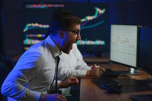 Team of traders working at monitor computer and browsing online in trading office photo