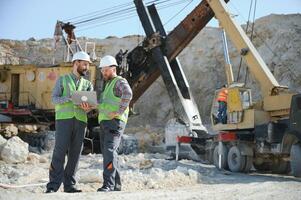 Portrait of stone quarry workers standing on the background of an excavator photo